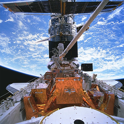 hubble telescope being visited by astronauts on a maintenance mission